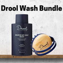 Drool Nourish My Coat Wash bundle featuring a matte navy blue bottle of coat wash and a natural bamboo grooming brush with a navy blue handle, displayed on a wooden shelf against a textured light gray wall.
